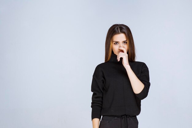 mulher de camisa preta parece emocionada e assustada.