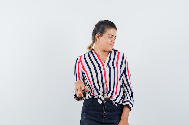 Mulher de camisa, saia posando olhando para o lado e parecendo glamorosa