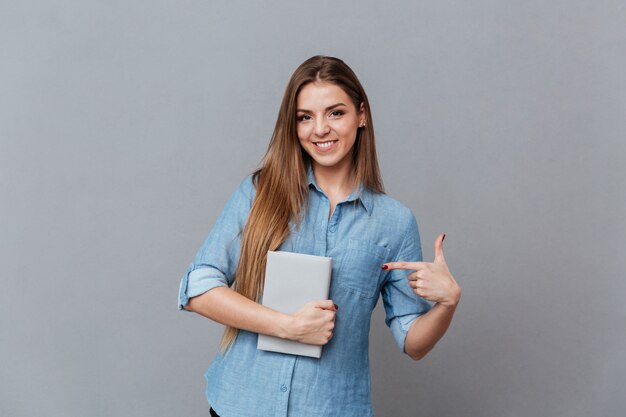 Mulher de camisa, segurando o livro na mão