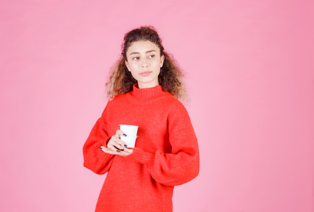 mulher de camisa vermelha, segurando uma xícara de café descartável.