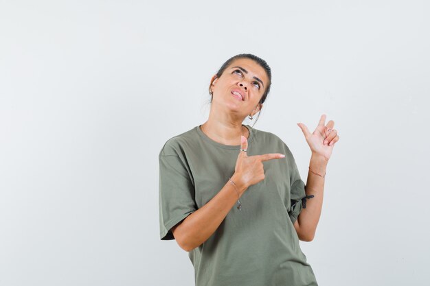 mulher de camiseta apontando para o lado e parecendo sonhadora