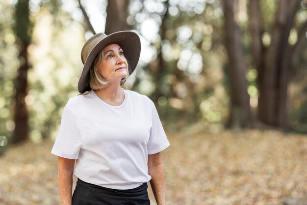 Mulher de camiseta branca apreciando a beleza da floresta