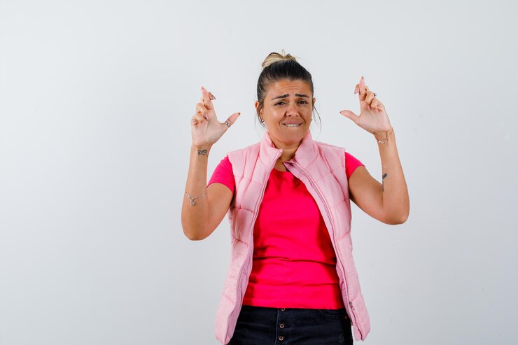 Foto grátis mulher de camiseta, colete com os dedos cruzados e parecendo esperançosa