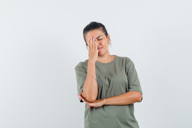 mulher de camiseta segurando a mão no rosto e parecendo pensativa