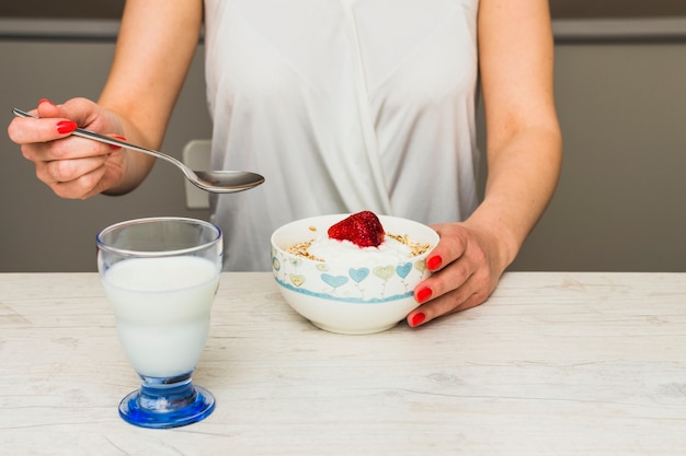 Mulher de colheita comer muesli com morango