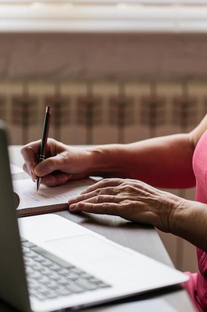 Foto grátis mulher de colheita perto de laptop fazendo anotações