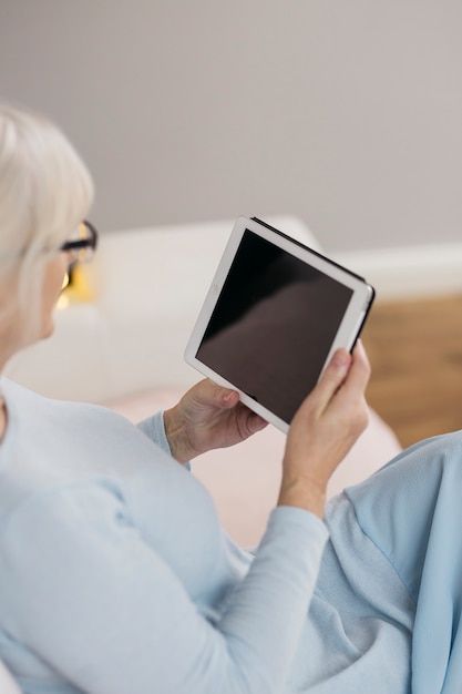 Mulher de colheita usando tablet no sofá