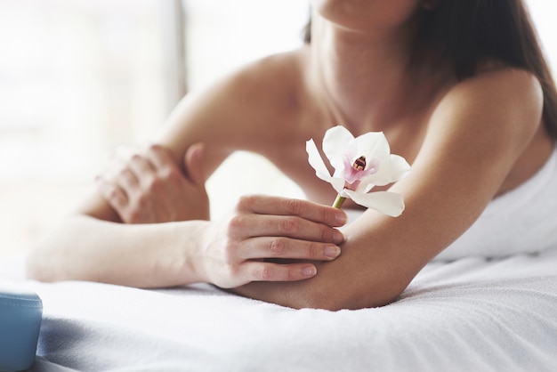 Mulher de corpo bonito com orquídea de flor branca e cuidados com o corpo.