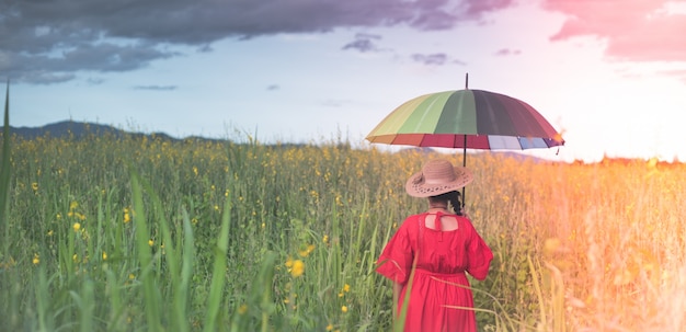 Mulher de costas olhando para um prado com um guarda-chuva