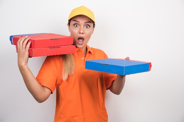 Mulher de entrega chocada segurando caixas de pizza.