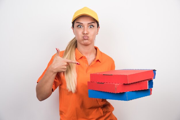 Mulher de entrega com chapéu amarelo, apontando caixas de pizza.