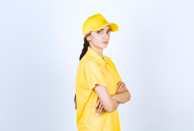 Mulher de entrega de uniforme amarelo em pé e olhando para a câmera.