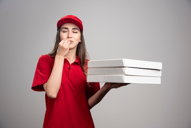 Mulher de entrega fazendo delicioso sinal sobre pizzas.