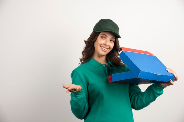 Mulher de entrega feliz em uniforme verde segurando a caixa de pizza aberta.