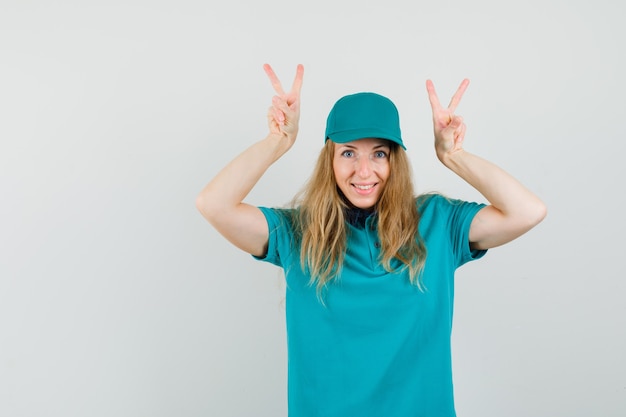 Foto grátis mulher de entrega mostrando v-sign em t-shirt, boné e parecendo engraçado.