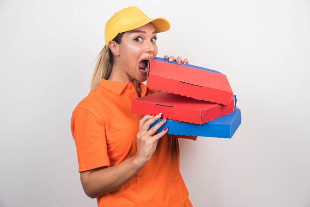 Mulher de entrega positiva tentando comer pizza no fundo branco.