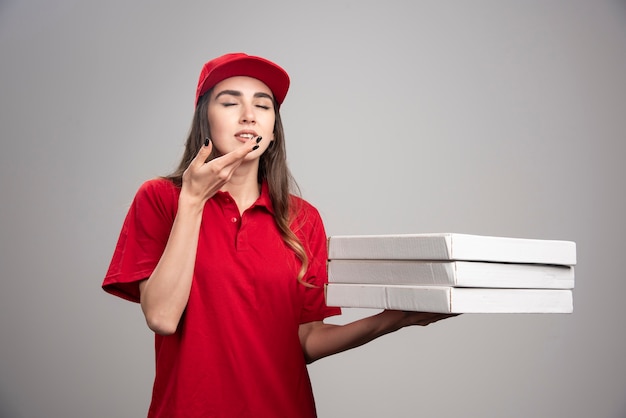 Mulher de entrega segurando pizzas de olhos fechados.