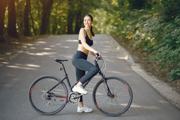 Mulher de esportes andando de bicicleta na floresta de verão