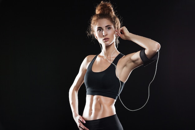Mulher de fitness posando e ouvindo música