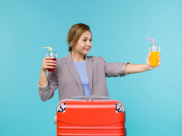 Mulher de frente para as férias, segurando bebidas frescas no fundo azul, viagem ao mar, férias, avião, viagem, viagem