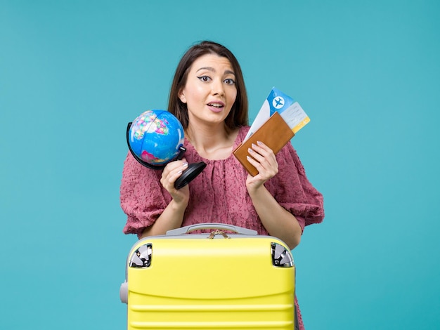 Mulher de frente para as férias segurando o globo e os bilhetes de avião na mesa azul, mar, férias, mulher, viagem, viagem, verão