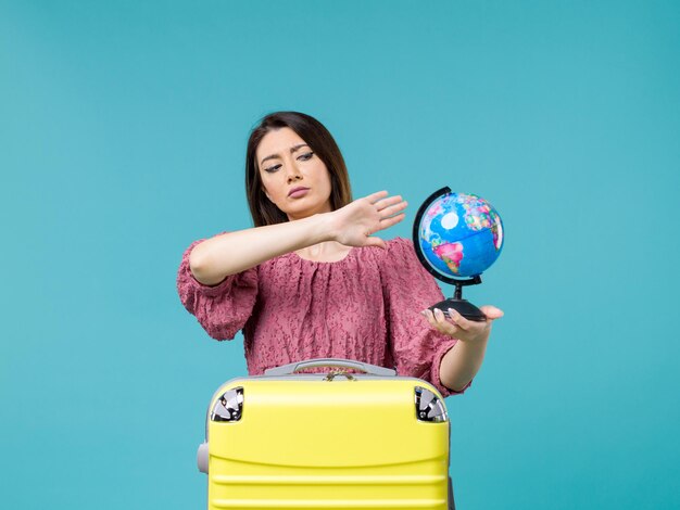 Foto grátis mulher de frente para as férias, segurando o pequeno globo terrestre no fundo azul, mar, férias, férias, verão, mulher, viagem