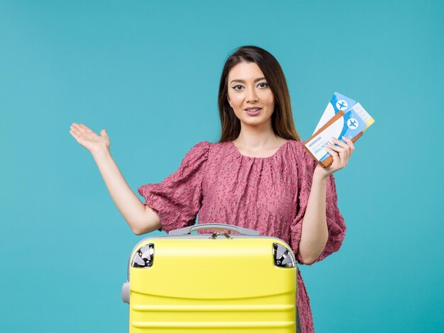 Mulher de frente para as férias segurando os ingressos no fundo azul viagem viagem verão mulher mar férias