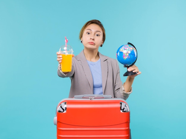 Mulher de frente para as férias segurando suco fresco e globo sobre fundo azul claro viagem ao mar viagem de férias