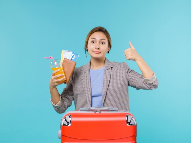 Mulher de frente para as férias, segurando uma bebida fresca e ingressos no fundo azul, viagem ao mar, viagem de férias, viagem