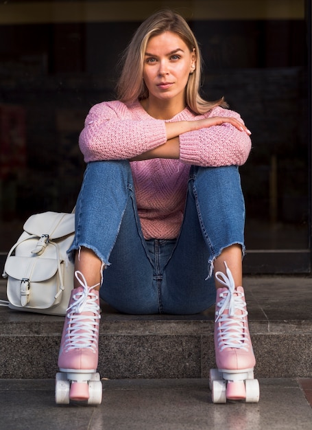 Mulher de jeans posando de patins com mochila