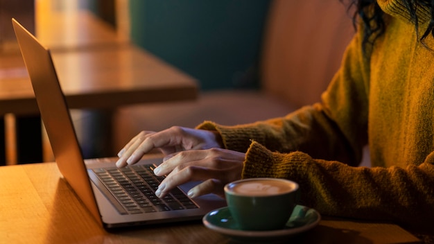 Mulher de lado trabalhando em seu laptop em uma cafeteria