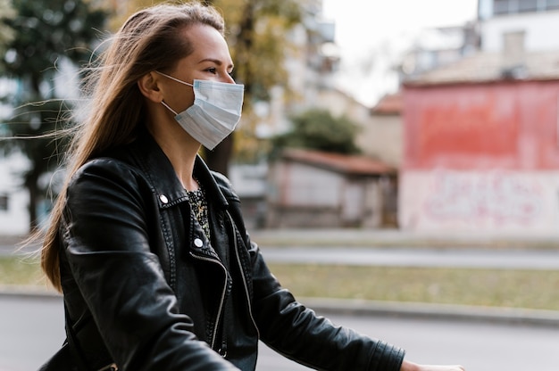 Foto grátis mulher de lado usando máscara e andando de bicicleta