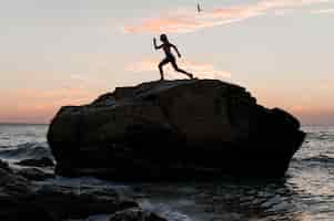 Foto grátis mulher de longo alcance em posição esportiva em uma rocha