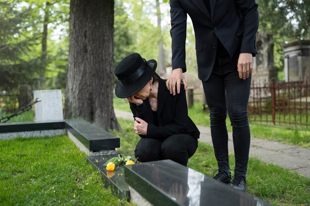 Mulher de luto no cemitério sendo consolada pelo homem