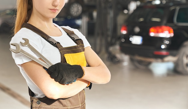 Mulher de macacão e luvas de proteção posando na oficina