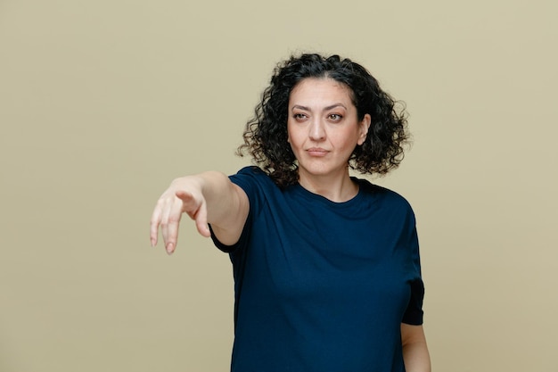 Foto grátis mulher de meia idade confiante vestindo camiseta olhando para o lado apontando para o lado isolado em fundo verde-oliva