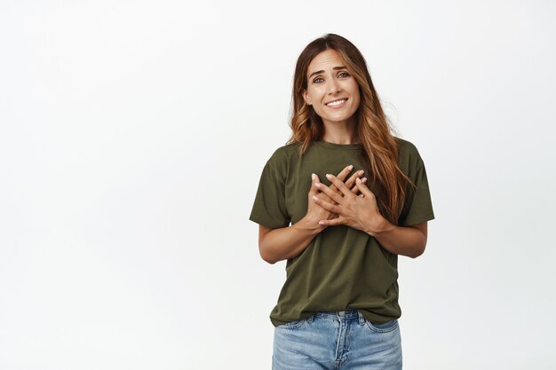 Mulher de meia-idade lisonjeada e tocada de mãos dadas no peito do coração, sorrindo satisfeita