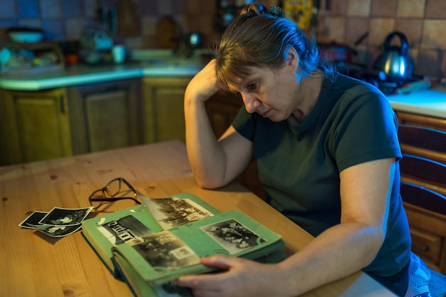 Mulher de meia idade olhando para o álbum de fotos da família memórias de tristeza nostalgia no conceito de meia idade