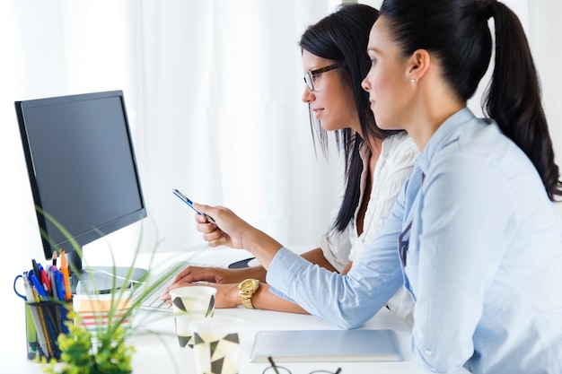 Mulher de negócio dois que trabalha no escritório com computador.