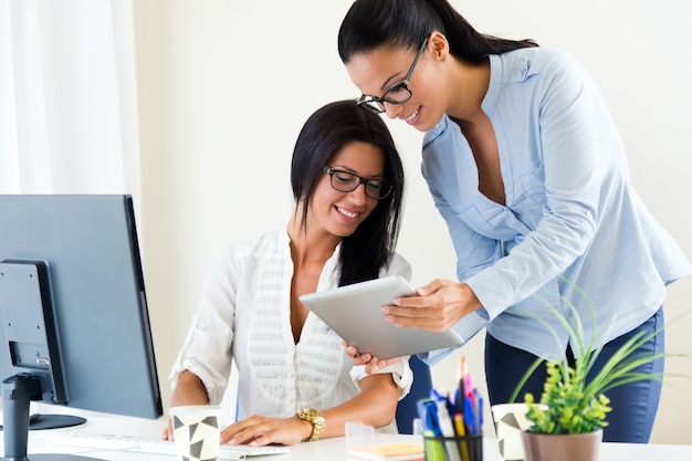 Mulher de negócio dois que trabalha no escritório com tabuleta digital.