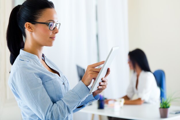 Mulher de negócio dois que trabalha no escritório com tabuleta digital.