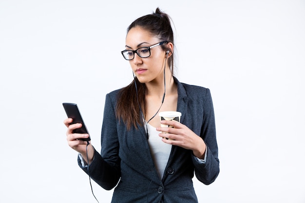 Mulher de negócio que usa seu telefone móvel e que bebe café.