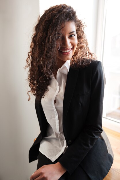 Mulher de negócios africana sorridente em pé perto da janela.