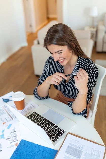 Mulher de negócios analisando dados usando o computador enquanto passa o tempo no escritório Linda jovem sorridente profissional no escritório Gráficos e gráficos