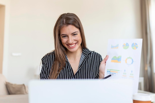 Mulher de negócios analisando dados usando o computador enquanto passa o tempo no escritório Linda jovem sorridente profissional no escritório Gráficos e gráficos