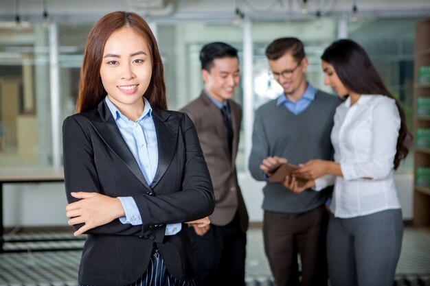 Mulher de negócios asiática bem sucedida com os colegas