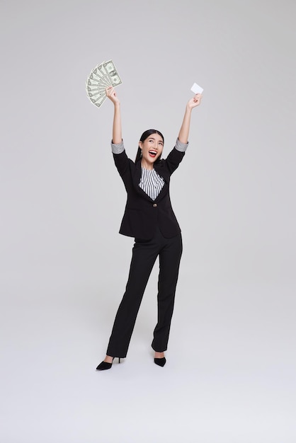 Foto grátis mulher de negócios asiática feliz mostrando apresentando cartão de crédito e dinheiro dólares sorrindo e rindo