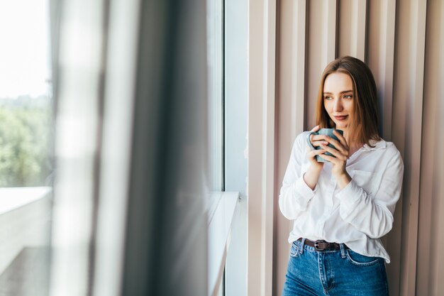 Foto grátis mulher de negócios atraente trabalhando em seu laptop e tomando café no escritório