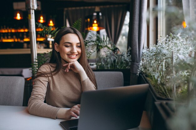Mulher de negócios, bebendo café e trabalhando no laptop em um café