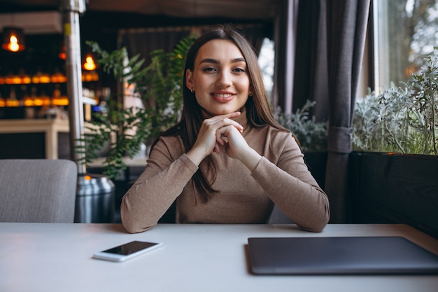 Mulher de negócios, bebendo café e trabalhando no laptop em um café